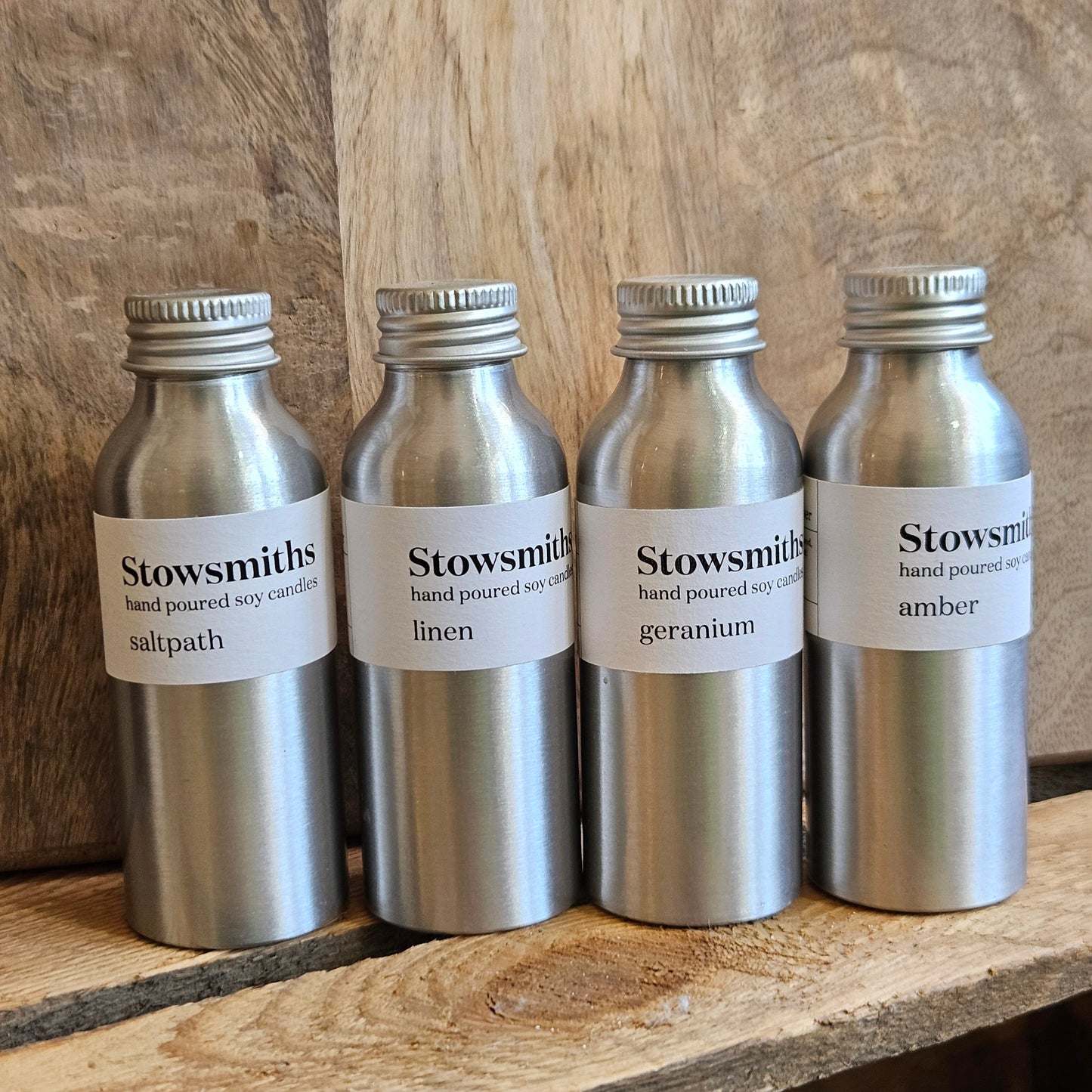 Four reed diffuser bottles on a wooden surface