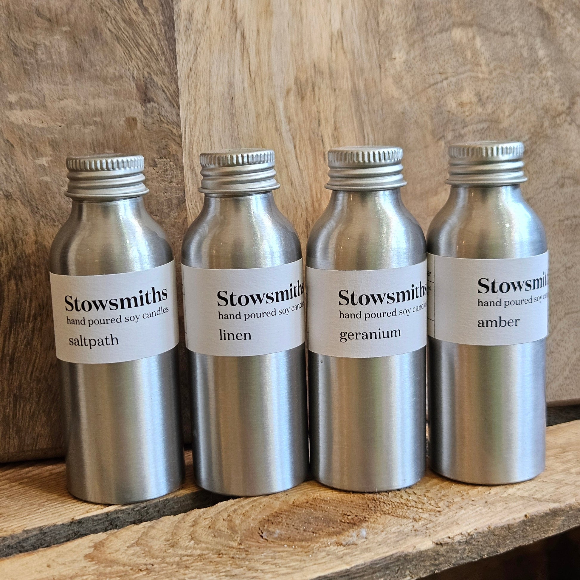 Four reed diffuser bottles on a wooden surface